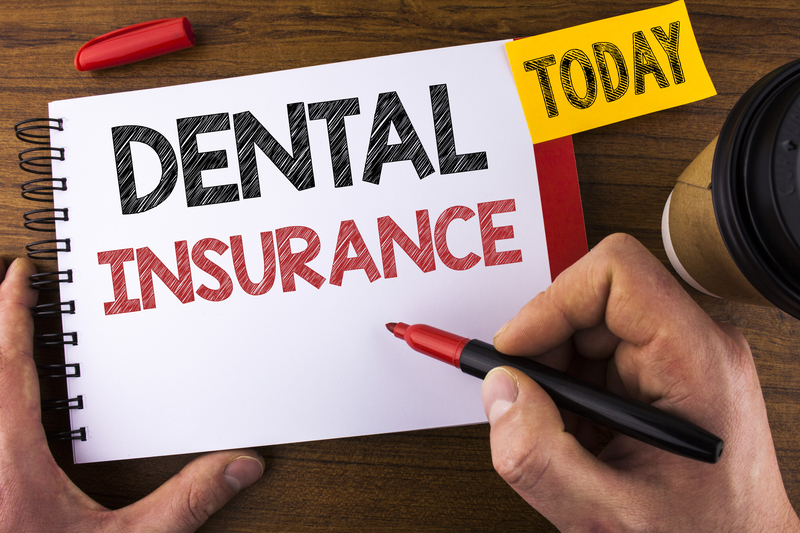 hands sketching the words "dental Insurance" in capitol letters